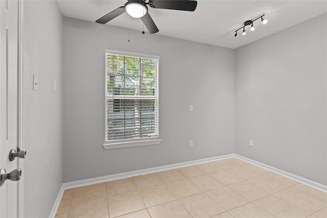 tiled spare room featuring a ceiling fan and baseboards