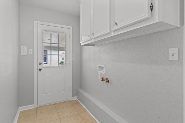 washroom featuring hookup for a washing machine, light tile patterned floors, cabinet space, and baseboards