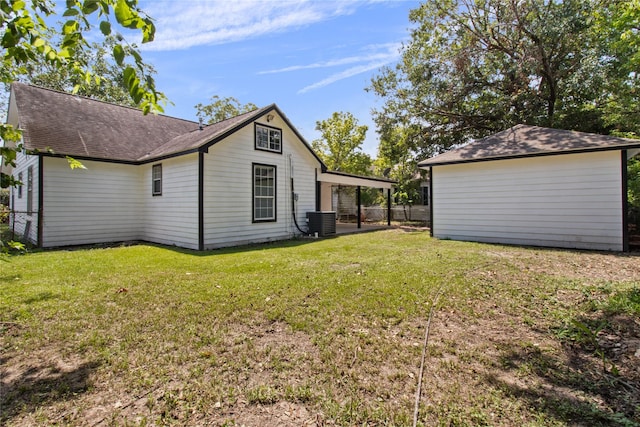 view of side of property featuring an outbuilding, a lawn, central AC unit, and fence