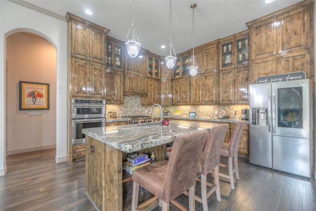 kitchen with light stone counters, backsplash, dark wood-style floors, and appliances with stainless steel finishes