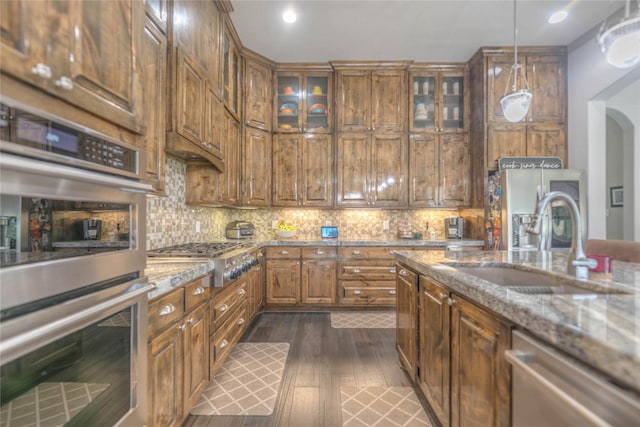 kitchen featuring a sink, decorative backsplash, light stone countertops, and stainless steel appliances