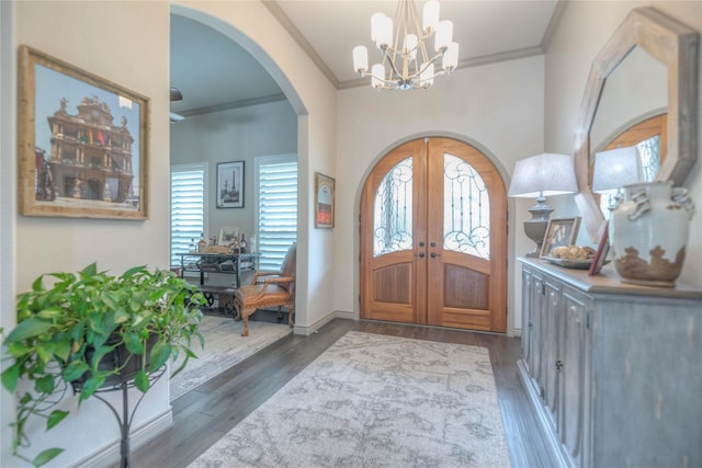 foyer entrance with french doors, arched walkways, wood finished floors, and crown molding