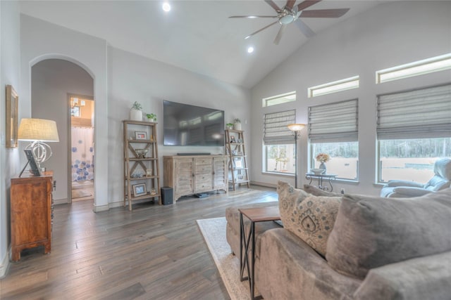 living area featuring wood finished floors, baseboards, high vaulted ceiling, arched walkways, and ceiling fan