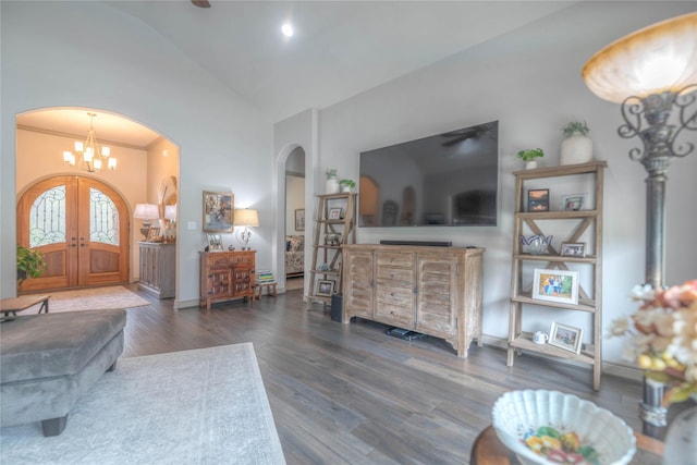 living area featuring high vaulted ceiling, wood finished floors, french doors, arched walkways, and an inviting chandelier