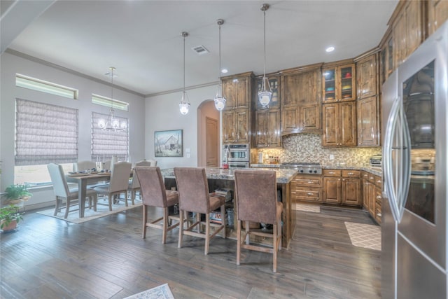 kitchen featuring backsplash, dark wood finished floors, brown cabinets, appliances with stainless steel finishes, and arched walkways