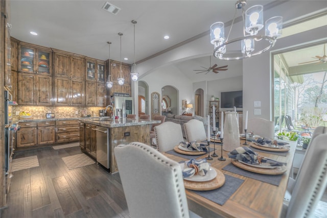 dining room with visible vents, ceiling fan, dark wood finished floors, lofted ceiling, and arched walkways