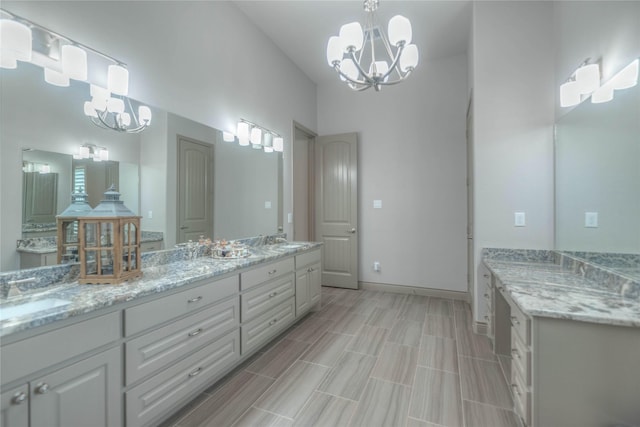 bathroom featuring double vanity, a notable chandelier, baseboards, and a sink