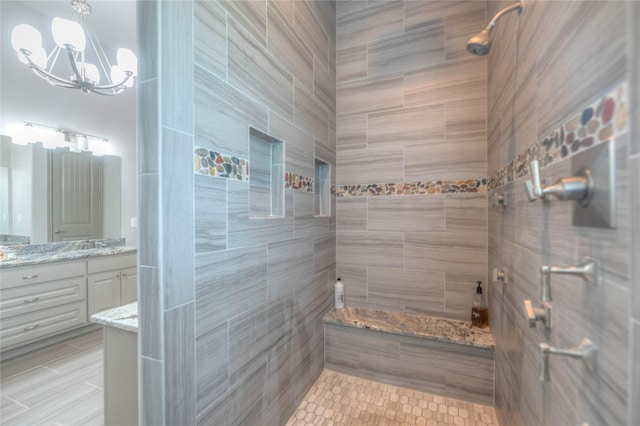 full bath featuring a chandelier, tiled shower, and vanity