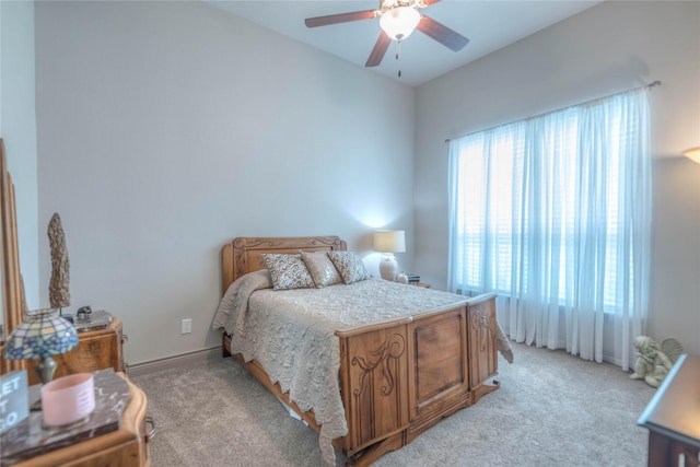 bedroom featuring baseboards, light colored carpet, and ceiling fan