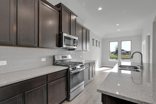 2512 Seneca Lake Dr, Texas City, TX 77568 - kitchen featuring stainless steel appliances, a sink, tasteful backsplash, light stone countertops, and light wood-type flooring
