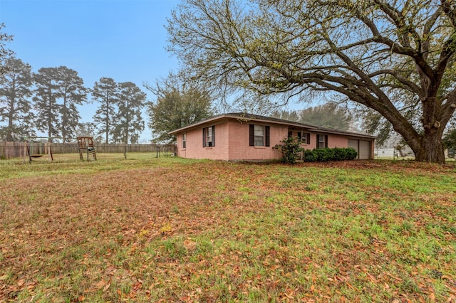 view of side of property with brick siding, a yard, a garage, and fence