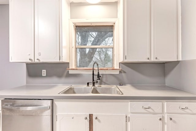 kitchen with stainless steel dishwasher, light countertops, white cabinetry, and a sink