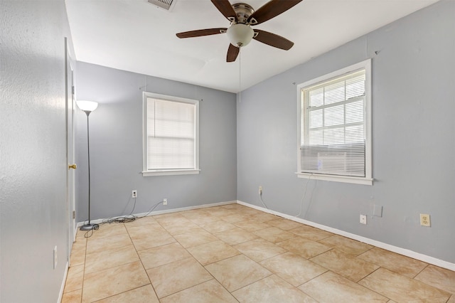 tiled spare room with visible vents, a ceiling fan, and baseboards