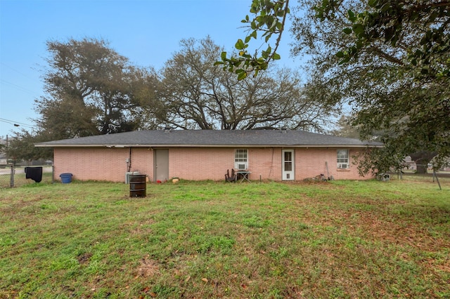 rear view of property with brick siding, a lawn, and fence