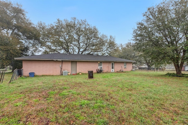 back of house featuring a yard, fence, brick siding, and central AC