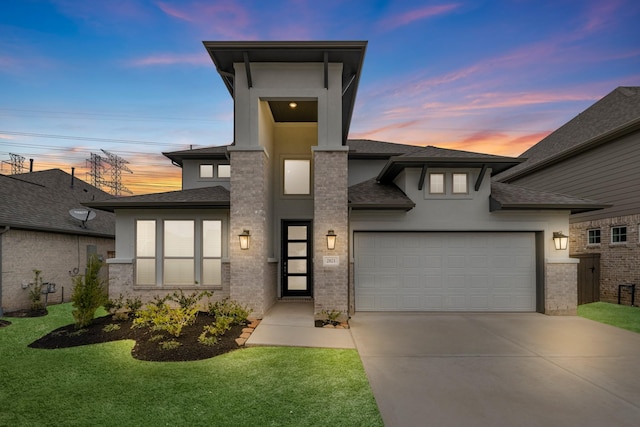 view of front of house with a yard, stucco siding, concrete driveway, a garage, and brick siding