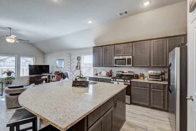kitchen with tasteful backsplash, visible vents, dark brown cabinets, vaulted ceiling, and stainless steel appliances