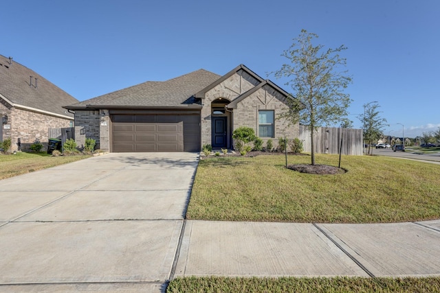 view of front facade featuring brick siding, fence, a front yard, a garage, and driveway