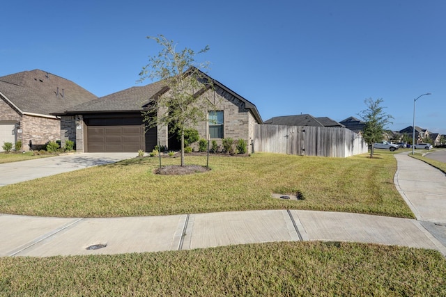 view of front of house featuring a front lawn, fence, concrete driveway, an attached garage, and brick siding