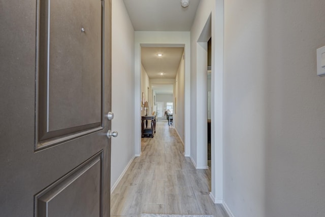 corridor featuring light wood-style flooring and baseboards