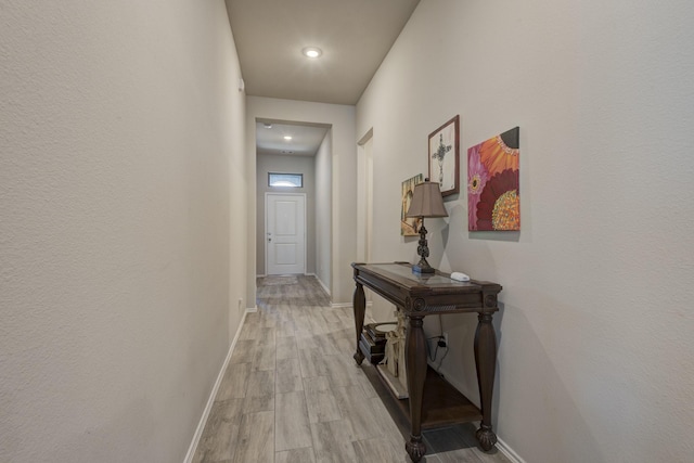 hallway with light wood-type flooring and baseboards