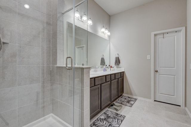 full bath with baseboards, double vanity, a stall shower, tile patterned floors, and a sink