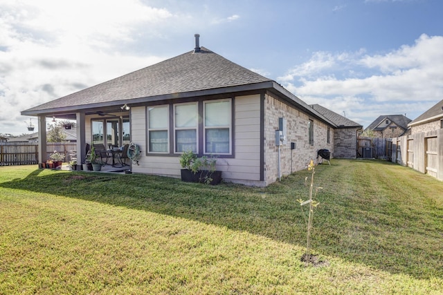 back of house with a patio, a fenced backyard, a yard, a shingled roof, and brick siding