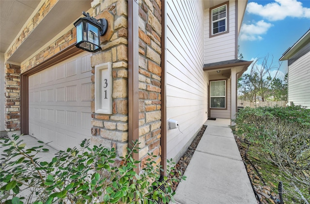 property entrance with a garage, brick siding, and stone siding