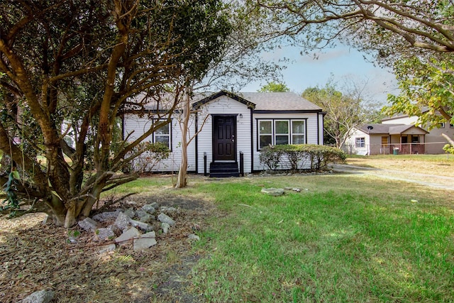 view of front facade with entry steps, a front lawn, and roof with shingles