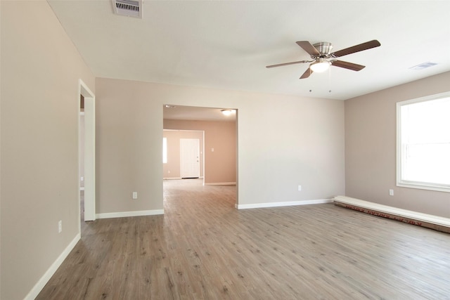 unfurnished room featuring light wood finished floors, visible vents, and baseboards