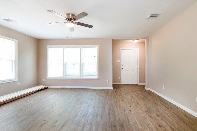 spare room with light wood-style floors, visible vents, and baseboards