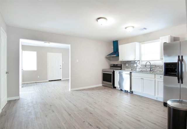 kitchen with a sink, a wealth of natural light, appliances with stainless steel finishes, and wall chimney exhaust hood