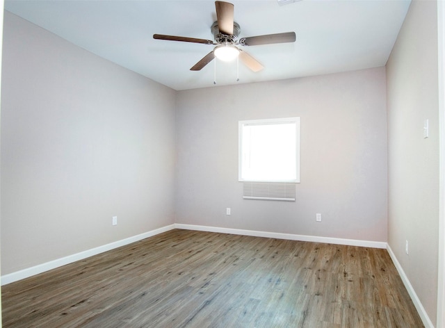 spare room with baseboards, wood finished floors, and a ceiling fan