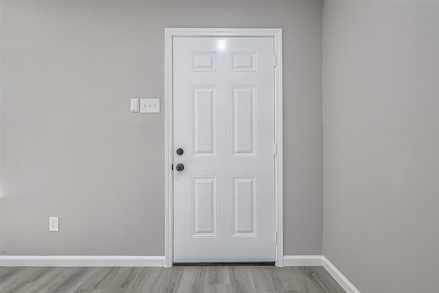 doorway featuring baseboards and wood finished floors