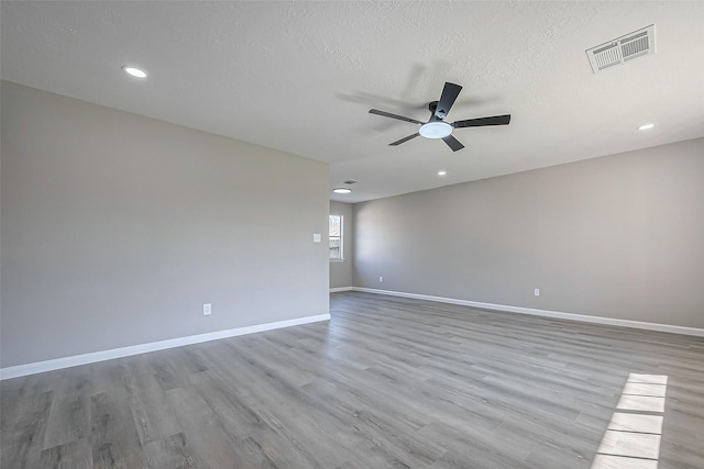 unfurnished room with visible vents, a textured ceiling, wood finished floors, baseboards, and ceiling fan