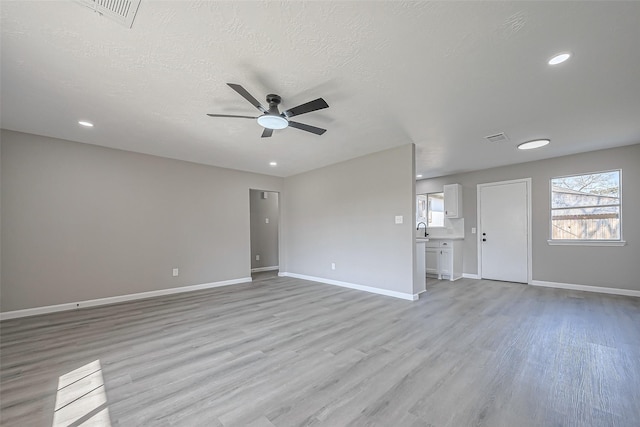 unfurnished room featuring baseboards, visible vents, a ceiling fan, and light wood-style floors