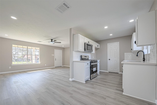 kitchen featuring visible vents, light countertops, decorative backsplash, appliances with stainless steel finishes, and a sink