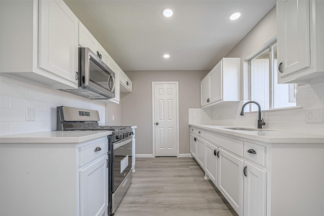 kitchen featuring a sink, light countertops, white cabinetry, and stainless steel appliances