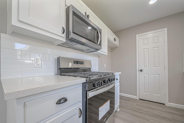 kitchen featuring light stone counters, backsplash, appliances with stainless steel finishes, and white cabinets