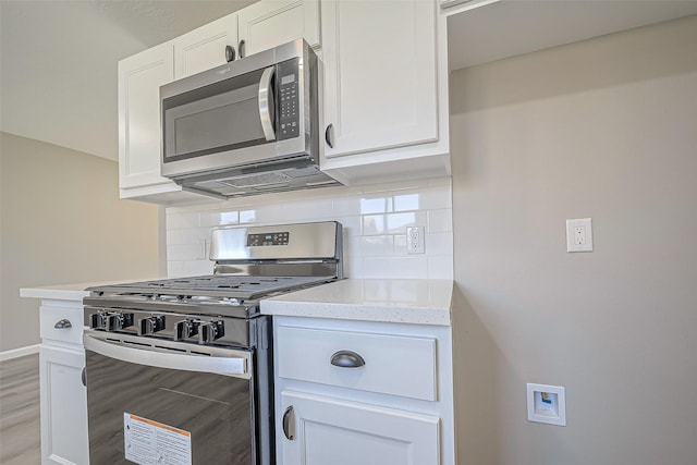 kitchen with stainless steel appliances, backsplash, and white cabinets