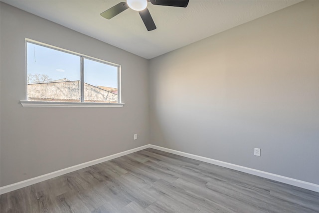 spare room featuring ceiling fan, baseboards, and wood finished floors