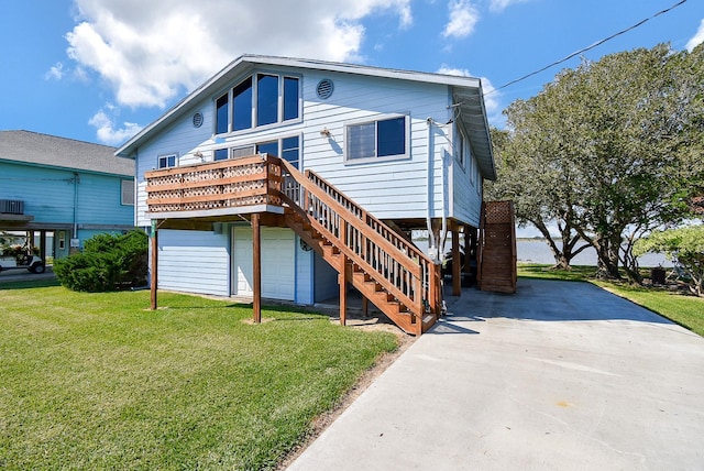 back of house with stairway, a lawn, a garage, and driveway