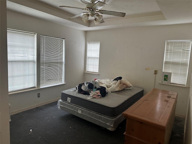 bedroom featuring a raised ceiling, baseboards, and ceiling fan