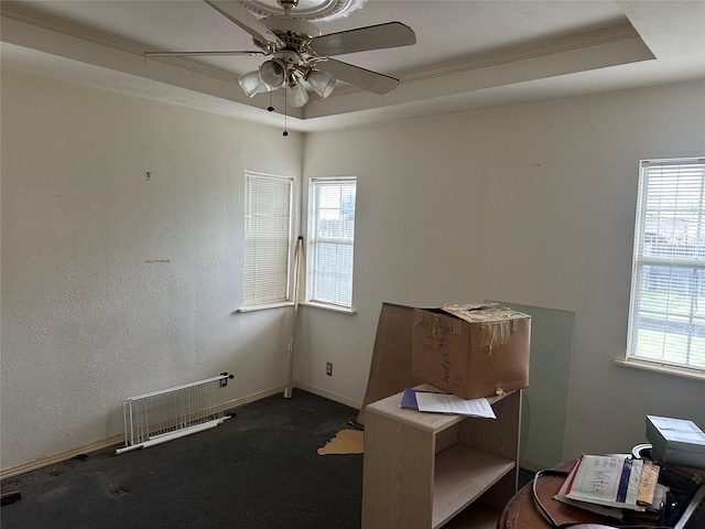 interior space with a wealth of natural light, visible vents, a raised ceiling, and a ceiling fan