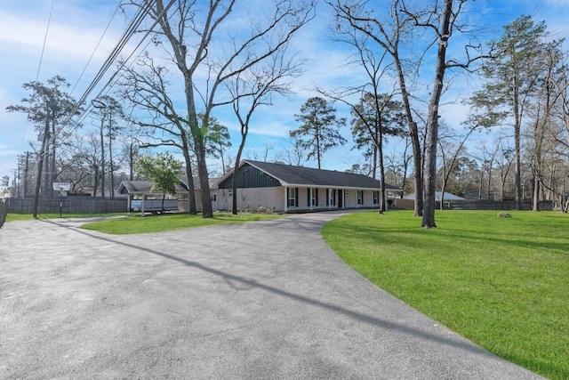 view of front of property featuring aphalt driveway, fence, and a front yard