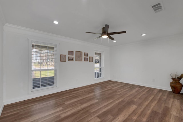 empty room featuring visible vents, plenty of natural light, dark wood-type flooring, and ornamental molding