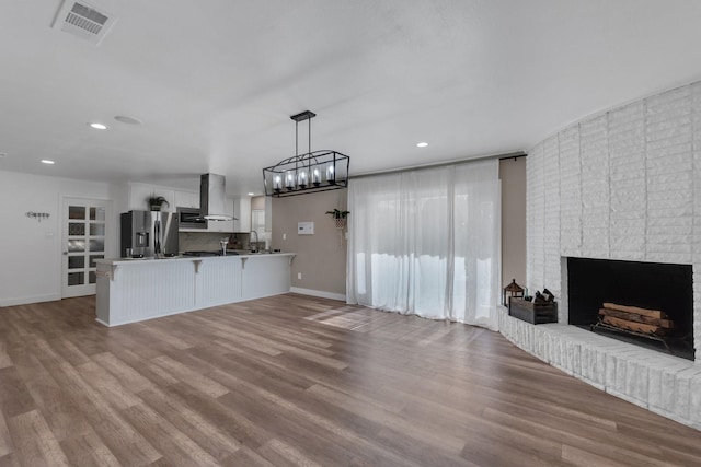 unfurnished living room with visible vents, baseboards, recessed lighting, a fireplace, and wood finished floors