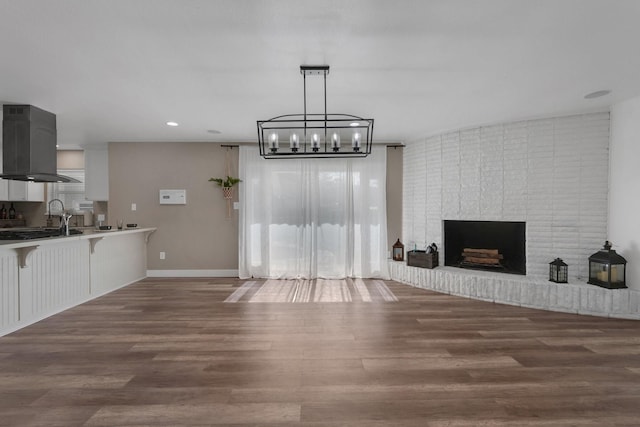 living room featuring recessed lighting, baseboards, a brick fireplace, and wood finished floors