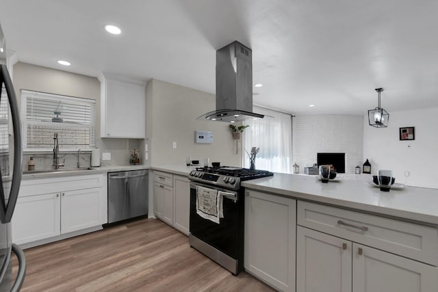 kitchen with light wood-style flooring, a sink, light countertops, appliances with stainless steel finishes, and island range hood