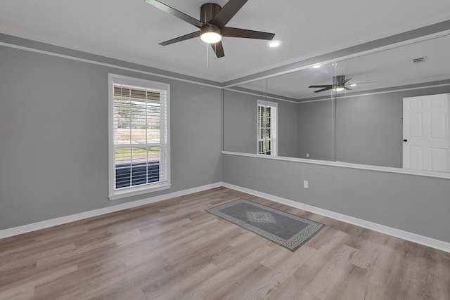 empty room with visible vents, a ceiling fan, baseboards, and wood finished floors